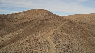 AX0011_053E - 5K aerial stock footage of a mountain road in Mojave Desert, California