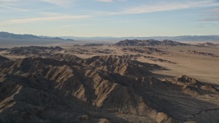 AX0011_070 - 5K stock footage aerial video fly by mountains revealing desert plain, Mojave Desert, California