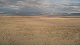 AX0011_071E - 5K aerial stock footage of an open plain in the Mojave Desert, California