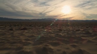 AX0012_039E - 5K stock footage aerial video fly low over desert plain toward the sun, Mojave Desert, California