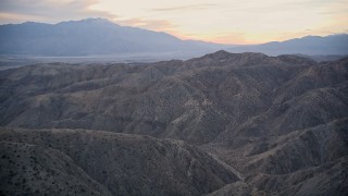 AX0012_063 - 5K aerial stock footage fly over canyons and desert mountains, Mojave Desert, California, sunset
