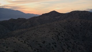 AX0012_066 - 5K aerial stock footage fly low over desert mountains, Mojave Desert, California, sunset