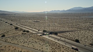 AX0013_019 - 5K aerial stock footage of interstate cutting through desert wind farm, San Gorgonio Pass Wind Farm, California
