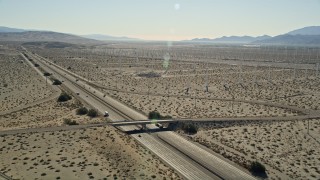 AX0013_024 - 5K aerial stock footage of flying over an interstate passing through desert and a windmill farm, Palm Springs, California