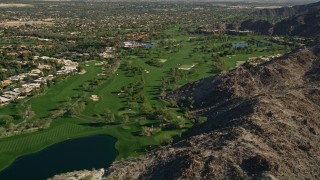 AX0013_077E - 5K aerial stock footage of a golf course bordered by mountains, Indian Wells, California