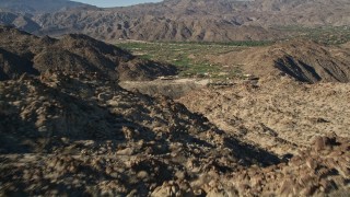 AX0013_081 - 5K aerial stock footage fly over mountain toward a valley community, Indian Wells, California