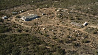 AX0014_023 - 5K aerial stock footage of orbiting a rural home with a greenhouse, Mountain Center, California