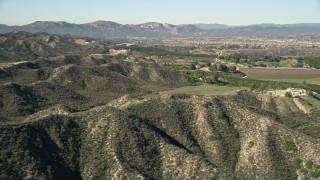 AX0014_033 - 5K aerial stock footage fly over hills toward farmland, Temecula, California
