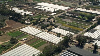 AX0015_009 - 5K aerial stock footage of orbiting farmland and greenhouse, Fallbrook, California