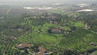 AX0015_035 - 5K aerial stock footage of large homes and farmland atop a hill, Fallbrook, California