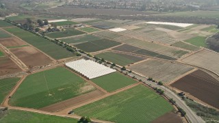 AX0015_044 - Aerial stock footage of 5K aerial  video of farmland and greenhouses beside a country road, Oceanside, California