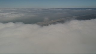 AX0016_014 - 5K aerial stock footage tilt from dense cloud layer to reveal the coastline, Camp Pendleton, California