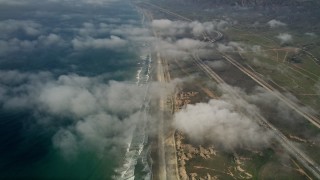 AX0016_027 - 5K aerial stock footage of an empty beach, follow the coast and fly over clouds, Oceanside, California