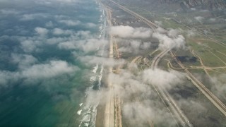 AX0016_028 - 5K aerial stock footage tilt from a bird's eye of the beach and fly over clouds to follow the coast, Oceanside, California