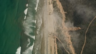 AX0016_030E - 5K aerial stock footage of a bird's eye of ocean waves rolling toward empty beach and cliffs, Oceanside, California