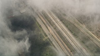AX0016_035 - 5K aerial stock footage of a bird's eye of light traffic on Interstate 5 through dense clouds, Oceanside, California