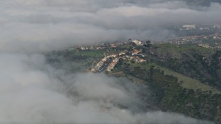 AX0016_038 - 5K aerial stock footage approach hillside suburban homes bordered by clouds, San Clemente, California