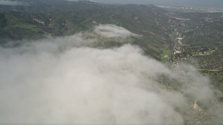 AX0016_061 - 5K aerial stock footage of green hills by the edge of a fog bank, Laguna Beach, California