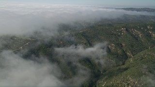 AX0016_062 - 5K aerial stock footage approach a dirt road atop hills near the edge of rolling fog, Laguna Beach, California