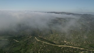 AX0016_064 - 5K aerial stock footage fly over green hills and rolling fog, Laguna Beach, California