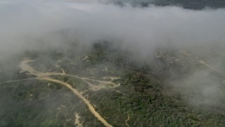AX0016_066 - 5K aerial stock footage tilt from fog over the hills to reveal and approach hilltop homes, Laguna Beach, California
