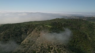 AX0016_068E - 5K aerial stock footage fly over hills and fog toward mountains ridge in Newport Beach, California