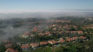 AX0016_070E - 5K aerial stock footage approach and fly over hilltop mansions near a fog bank, Newport Beach, California