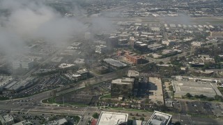AX0016_081 - 5K aerial stock footage tilt down to office buildings on MacArthur Boulevard, seen through misty clouds, Newport Beach, California
