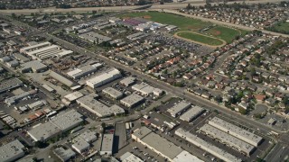 AX0016_101 - 5K aerial stock footage tilt from warehouses to reveal Los Alamitos High School, residential neighborhoods, and Coyote Creek, Los Alamitos, California