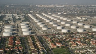 AX0017_008E - 5K aerial stock footage approach residential neighborhood and storage tanks, Carson, California
