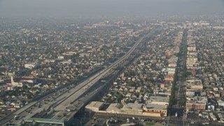AX0017_039 - 5K aerial stock footage of Interstate 110 with traffic, tilt to reveal neighborhoods, South Central Los Angeles