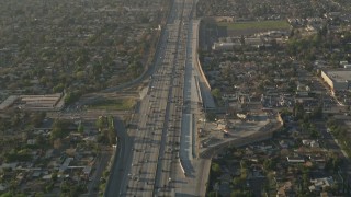 AX0017_117 - 5K aerial stock footage of following heavy interstate traffic through neighborhoods, Pacoima, California, sunset