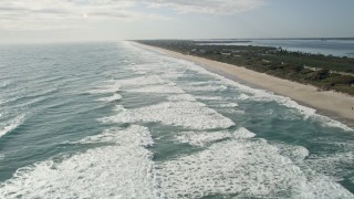 AX0018_074E - 5K aerial stock footage fly over ocean waves by Melbourne Beach in Florida