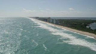 AX0019_004E - 5K aerial stock footage of following the beach toward Jensen Beach apartment buildings in Florida