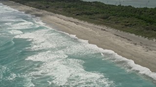AX0019_033 - 5K aerial stock footage of waves lapping beach in Tequesta, Florida