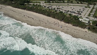 AX0019_039 - 5K aerial stock footage of sunbathers enjoying a Jupiter beach as waves roll in, Florida
