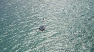 AX0019_050 - 5K aerial stock footage flyby a parasailer in the clear blue ocean by Riviera Beach, Florida