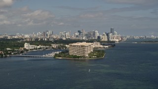 AX0020_005 - 5K aerial stock footage approach condo complexes on Grove Isle with Downtown Miami skyline in background, Florida