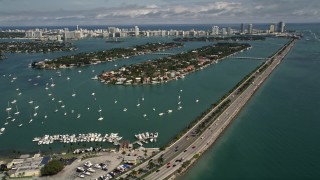 AX0020_034 - 5K aerial stock footage of MacArthur Causeway by sailboats moored in the bay, and Palm and Hibiscus Islands in Miami, Florida