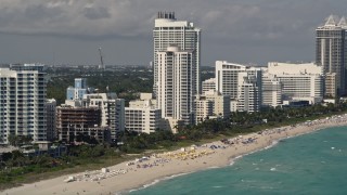 AX0020_051E - 5K aerial stock footage approach beachfront Fontainebleau Miami Beach Hotel with crowded beach in Florida
