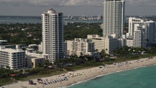 AX0020_053 - 5K aerial stock footage of beachfront hotels and sunbathers by the ocean in Miami Beach, Florida