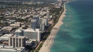 AX0020_063 - Aerial stock footage of Flyby Beachfront Hotels and Tilt to Sunbathers in Miami Beach 