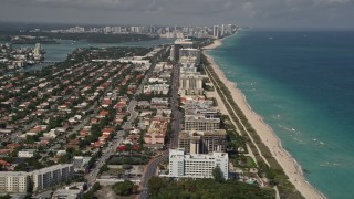 AX0020_066 - 5K aerial stock footage follow Collins Avenue by coastal neighborhoods and beachside condos in Surfside, Florida