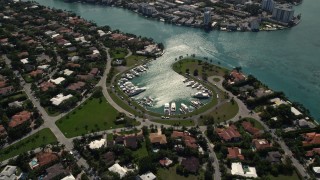 AX0020_092 - 5K aerial stock footage fly over coastal neighborhood to approach boats in small marina in Bal Harbour, Florida