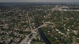 AX0020_104 - 5K aerial stock footage of canal beside school and suburban neighborhoods in Biscayne Park, Miami, Florida
