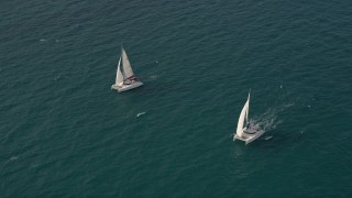 AX0021_037E - 5K aerial stock footage tilt from calm ocean water to reveal and orbit two catamarans near South Beach, Florida