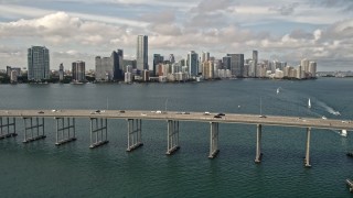 AX0021_115E - 5K aerial stock footage tilt to reveal and approach Rickenbacker Causeway and Downtown Miami skyline, Florida