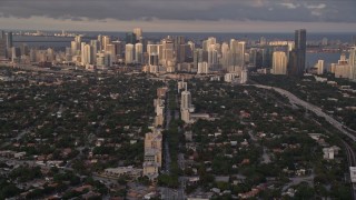 AX0022_023 - 5K stock footage aerial video tilt from Coral Gables suburbs to reveal Downtown Miami at sunset in Florida