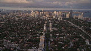 AX0022_024 - 5K aerial stock footage of following SW 3rd Avenue through suburbs to approach Downtown Miami at sunset, Florida