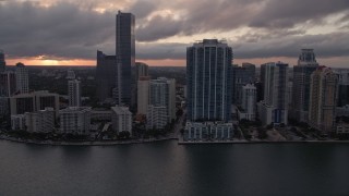 AX0022_056E - 5K aerial stock footage tilt from bay to reveal and approach Downtown Miami skyline at sunset in Florida